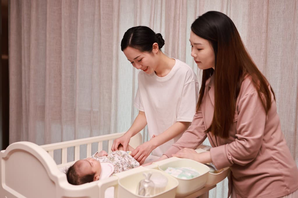 A parent holding a newborn during an in-home postpartum visit.